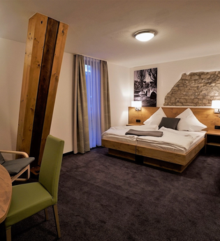 Ein Hotelzimmer mit Doppelbett und Sitzgelegenheit | © Touristikgemeinschaft Hohenlohe e. V. | Rebenhof Fröscher, Forchtenberg