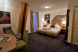 Ein Hotelzimmer mit Doppelbett und Sitzgelegenheit | © Touristikgemeinschaft Hohenlohe e. V. | Rebenhof Fröscher, Forchtenberg