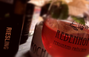 Ein Weinglas und Flaschen dahinter mit dem Logo vom Rebenhof Fröscher | © Touristikgemeinschaft Hohenlohe e. V.  | Rebenhof Fröscher