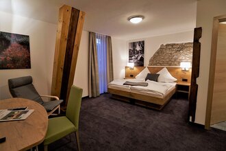 Ein Hotelzimmer mit Doppelbett und Sitzgelegenheit | © Touristikgemeinschaft Hohenlohe e. V. | Rebenhof Fröscher, Forchtenberg