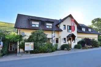Außenansicht des Landgasthofs Taubertal mit gelbem Gebäude, braunem Dach und Schildern am Eingang | © Landgasthof Taubertal