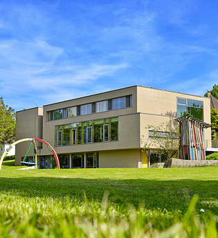 Außenansicht der Heimvolkshochschule mit Fenstern und grünem Garten | © Touristikgemeinschaft Hohenlohe e. V. | Ländliche Heimvolkshochschule Hohebuch