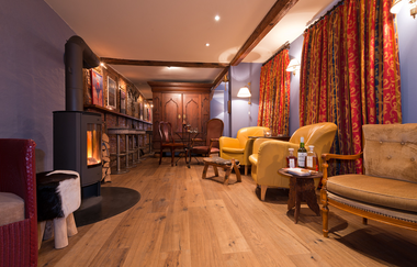 Blick in das Kaminzimmer "Dubra" im Hotel Laurentius in Weikersheim. Hier ist ein Kaminofen mit loderndem Feuer, eine Bar und einige Sessel zu sehen. Im Hintergrund steht ein antiker Schrank. | © Unbekannt