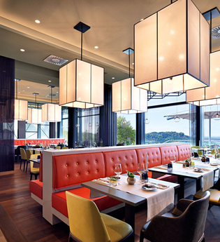 Das Restaurant ist mit roten Sitzbänken und modernen Stühlen und Leuchten ausgestattet | © Touristikgemeinschaft Hohenlohe e. V. |  Panoramahotel Waldenburg – Mellenthin