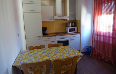 Aufnahme der Küche: ein Esstisch mit 4 Holzstühlen, mehrere weiße Schränke und eine Mikrowelle, Kaffeemaschine, dazu noch Herdplatte und Ofen. | © Neckar-Zaber-Tourismus e.V.