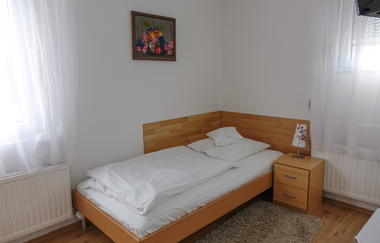 Bild des Einzelzimmers: Bett mit Nachttischschränkchen und Lampe, Zwei Fenster | © Neckar-Zaber-Tourismus e.V.