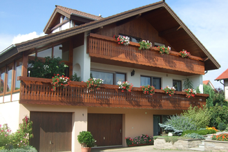 Das Gebäude hat zwei Holzbalkone, an denen Blumen blühen | © Touristikgemeinschaft Hohenlohe e. V. | Familie Beez