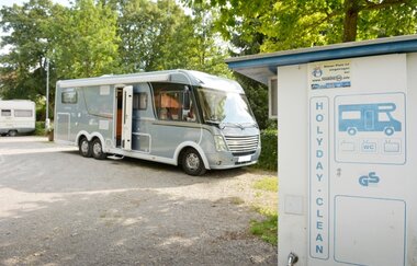 Auf einem Platz steht ein graues Wohnmobil. Dahinter sind Bäume zu sehen. Im Vordergrund stehe eine Clean-Station. Walldürn im Odenwald. | © Stadt Walldürn - Touristinformation