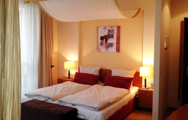 Gemütliches Doppelzimmer, Nachttischen mit Lampen, Vorhängen und abstraktem Bild an der Wand | © Ringhotel Bundschu