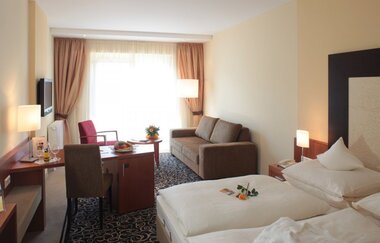 Doppelzimmer im Hotel Bundschu, Schreibtisch, Sofa, Fernseher und großen Fenstern mit Vorhängen | © Ringhotel Bundschu