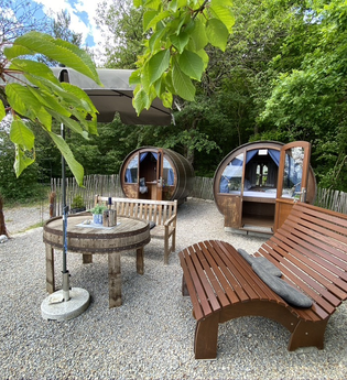 Zwei Weinfässer mit einem Außenbereich. Auf dem Kiesbett stehen Sitzbänke und Tische, der Bereich ist eingezäunt. | © Jakobshof Lehr