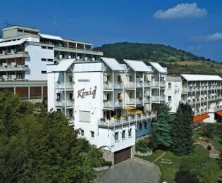 Außenansicht des Vitalhotels König, ein mehrstöckiges weißes Hotelgebäude umgeben von Bäumen und Hügeln unter blauem Himmel | © Vitalhotel König