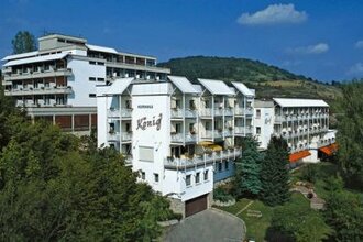 Außenansicht des Vitalhotels König, ein mehrstöckiges weißes Hotelgebäude umgeben von Bäumen und Hügeln unter blauem Himmel | © Vitalhotel König