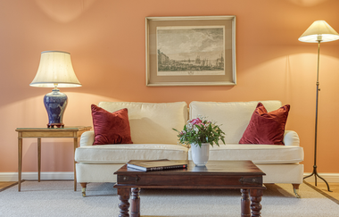 Vor der eleganten Couch in weiß steht ein antiker Tisch | © Touristikgemeinschaft Hohenlohe e. V. | Wald & Schlosshotel Friedrichsruhe