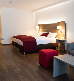 Hotelzimmer mit Doppelbett, Couch und kleiner Essecke | © Touristikgemeinschaft Hohenlohe e. V.