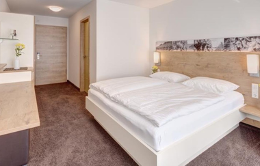 Modernes Doppelbett mit weißer Bettwäsche, Schreibtisch und TV | © Touristikgemeinschaft Hohenlohe e. V.