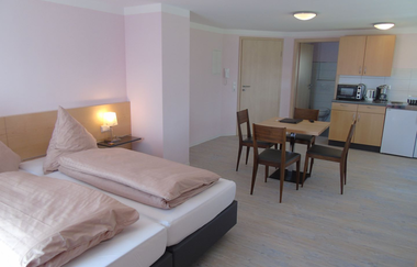 Im Appartement steht ein Doppelbett, ein Tisch mit Stühlen und eine Küchenzeile | © Touristikgemeinschaft Hohenlohe e. V.