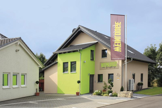 Gebäude von Außen zu sehen mit grünem und braunen Farben und einer großen Fahne im Vordergrund mit Weinlodge