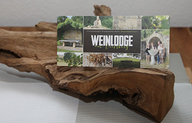 Holzstück mit Postkarte der Weinlodge darauf