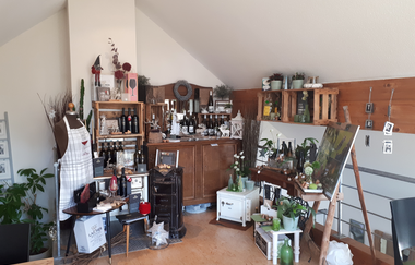 Vinothek mit vielen Regalen, Weinkisten, Mannequinpuppe, Schürze, Weine, viele Souvenirs | © Weinodge am Geisberg