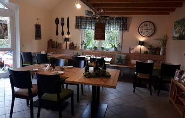 Weinstube mit Sitzgelegenheiten zum Essen, urige Dekoration an den Wänden und großer Uhr neben einem Fenster | © Weinlodge am Geisberg