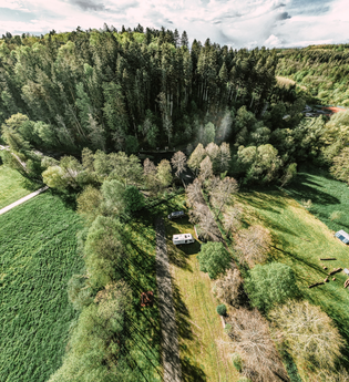 Aufnahme von der Luft aus, ein Wald mit einem Freibad sowie ein Wohnmobilsgtellplatz mit zwei Wohnmobilen. Buchen im Odenwald | © Touristikgemeinschaft Odenwald e.V.