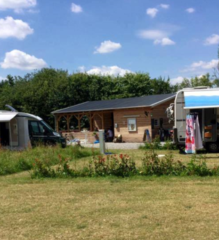 Man sieht einen Wohnwagen und ein Wohnmobil, beide mit heraugelassener Markise. In der Mitte ist ein Holzhaus. Schwarzach im Odenwald.
