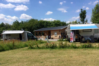 Man sieht einen Wohnwagen und ein Wohnmobil, beide mit heraugelassener Markise. In der Mitte ist ein Holzhaus. Schwarzach im Odenwald.