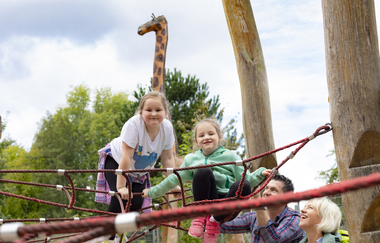 2 Kinder auf einem Klettergerüst. Die Eltern stehen davor. Im Hintergrund ist ein lebensgroße Holzgiraffe. Schwarzach im Odenwald. | © Touristikgemeinschaft Odenwald e.V.