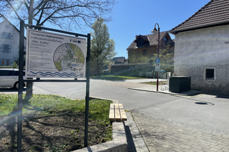 Eine Informationstafel im Vordergrund. Auf der rechten Seite steht ein Haus. Haßmersheim i Odenwald. | © Stadt Haßmersheim