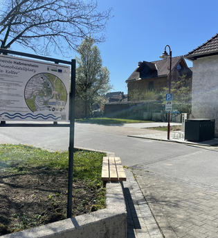 Eine Informationstafel im Vordergrund. Auf der rechten Seite steht ein Haus. Haßmersheim i Odenwald. | © Stadt Haßmersheim