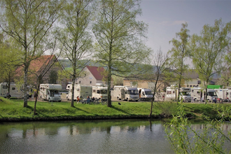 Blick auf den direkt an der Tauber gelegenen Wohnmobilstellplatz in Röttingen. Der Platz ist gut besucht. Im Hintergrund sind Häuser zu sehen. | © Tourist-Information Röttingen