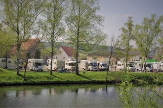 Blick auf den direkt an der Tauber gelegenen Wohnmobilstellplatz in Röttingen. Der Platz ist gut besucht. Im Hintergrund sind Häuser zu sehen. | © Tourist-Information Röttingen