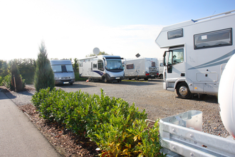 Ein geschotterter Platz mit vielen weißen Wohnmobilen. Im Vordergrund wird der Platz durch eine grüne Hecke begrenzt. Walldürn im Odenwald. | © Goldschmitt techmobil GmbH