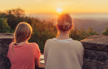2 Frauen stehen am Rand eines Turms und schauen in die Weite und den Sonnenuntergang. Katzenbuckel im Odenwald | © Touristikgemeinschaft Odenwald e.V.