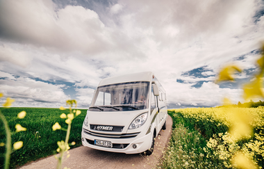 Ein weißes Wohnmobil. Auf der linken Seite eine großes grünes Feld. Auf der rechten Seite ein gelbes Rapsfeld. Odenwald. | © Touristikgemeinschaft Odenwald e.V.