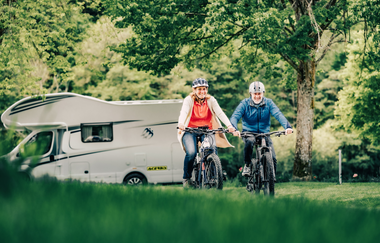 Zwei Radfahrer im Hintergrund ein weißes Wohnmobil und Bäume. Odenwald. | © Touristikgemeinschaft Odenwald e.V.