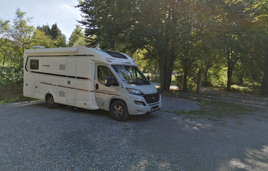 Ein weißes Wohnmobil im Schatten von Bäumen auf einem geschotterten Platz. Elztal im Odenwald. | © Erhard und Elvira Schneider "Zum Forellenbauer" GbR