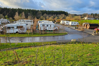 Ein Wohnmobilstellplatz mit vielen weißen Wohnmobilen. Im Vordergrund eine Wiese. Im Hintergrund ein Wald. Mudau im Odenwald. | © Golfclub Mudau und Freizeitanlagen GmbH
