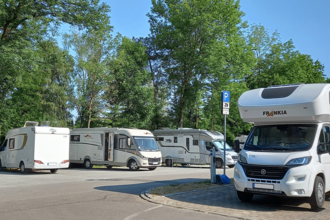 Wohnmobilstellplatz mit mehreren geparkten Wohnmobilen und Bäumen im Hintergrund. | © Stadt Gaildorf