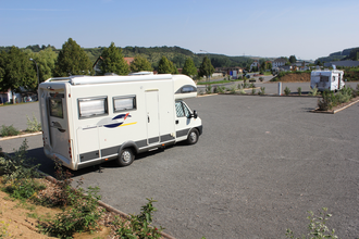 Ein weißes Wohnmobil im Vordergrund auf einem Stellplatz. Im Hintergrund ein kleines Wohnmobil. Hardheim im Odenwald.