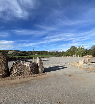 Einfahrt zu einem Wohnbmobilstellplatz. Die Begrenzung ist aus großen Findlingsteinen. Im Hintergrund sind Bäume. Limbach im Odenwald. | © Wohnmobilstellplatz Schuler