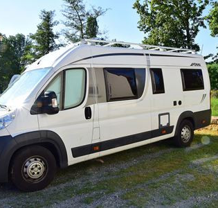 Blick auf den Wohnmobilstellplatz in Markelsheim.  Hier steht ein weißes Wohnmobil auf einer mit Rasengittersteinen ausgelegten Fläche. Im Hintergrund sind Bäume zu sehen. | © Unbekannt
