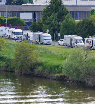 Ein Fluß an dessen Ufer ein Wohnmobilstellplatz ist. Es stehen mehrere Stellplätze in Reihe auf einer Wiese. Obrigheim im Odenwald. | © Gemeinde Obrigheim