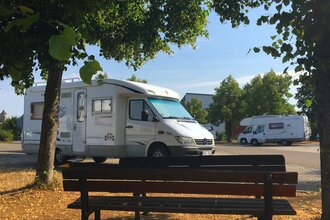 Blick auf eine Bank am Wohnmobilstellplatz P2 in Rothenburg o.d.T., umrahmt von Bäumen. | © Liebliches Taubertal