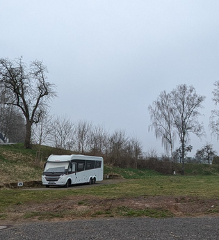 Es ist ein weißes Wohnmobil zu sehen. Dieses steht auf einem Platz im grünen. Im Hintergrund sind Bäume zu sehen. Der Platz ist in der Stadt Ravenstein im Odenwald | © Stadt Ravenstein