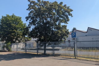 Es ist ein Parkplatz mit einem Wohnmobilschild zu sehen, begrenzt durch einen Zaun. Hinter dem Zaun steht ein Fabrikgebäude. Odenwald. | © Gemeinde Schefflenz