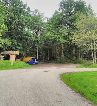 Ein Parkplatz am Waldrand. Auf dem Platz stehen zwei Fahrzeuge. Davor führt ein Weg vorbei. Schönbrunn im Odenwald. | © Gemeinde Schönbrunn
