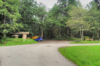 Ein Parkplatz am Waldrand. Auf dem Platz stehen zwei Fahrzeuge. Davor führt ein Weg vorbei. Schönbrunn im Odenwald. | © Gemeinde Schönbrunn
