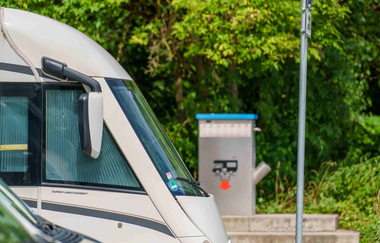 Wohnmobilstellplatz mit Wohnmobilen und Entsorgungsstation im Hintergrund. | © Michael Kuehneisen